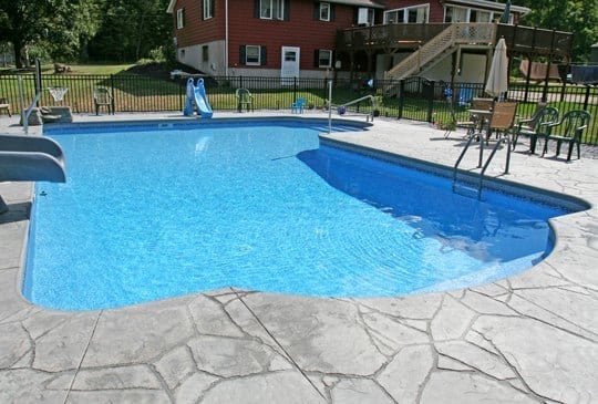 Inground pool with new liner that is surrounded by stonework, installed by juliano's pools near lexington, sc.