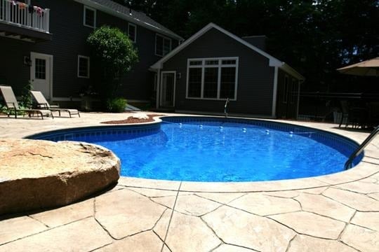 A kidney shaped pool witih deep blue water installed by julliano's pools near lexington, sc.